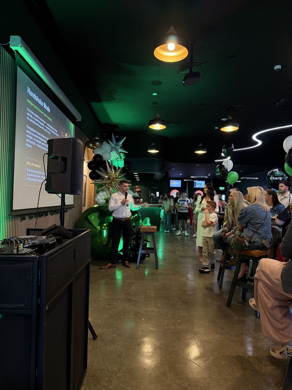 Guests gathered around a presentation screen and speaker